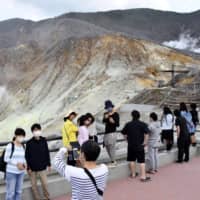 Tourists take photos in Hakone, Kanagawa Prefecture, on May 30, as Japan slowly reopens tourism and other businesses after lifting its state of emergency earlier in the month. | KYODO