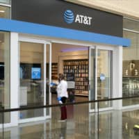 A worker wearing a protective mask disinfects the doors of an AT&T Inc. store in Dallas, Texas, on May 1. | BLOOMBERG