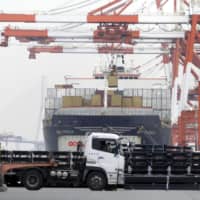A container is loaded onto a container ship at a shipping terminal in Yokohama, near Tokyo, on March 30. | BLOOMBERG