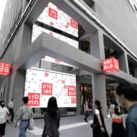 Pedestrians walk past Uniqlo Tokyo ahead of the store’s grand opening the following day. | BLOOMBERG