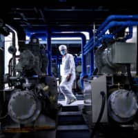 A worker wearing a protective suit walks at a lab where researchers are trying to develop a COVID-19 vaccine in Shenyang, China, on June 9. | AFP-JIJI