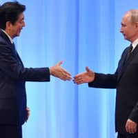 Russia\'s President Vladimir Putin shakes hands with Prime Minister Shinzo Abe during a news conference after the G20 Summit in Osaka in June 2019. | POOL / VIA REUTERS
