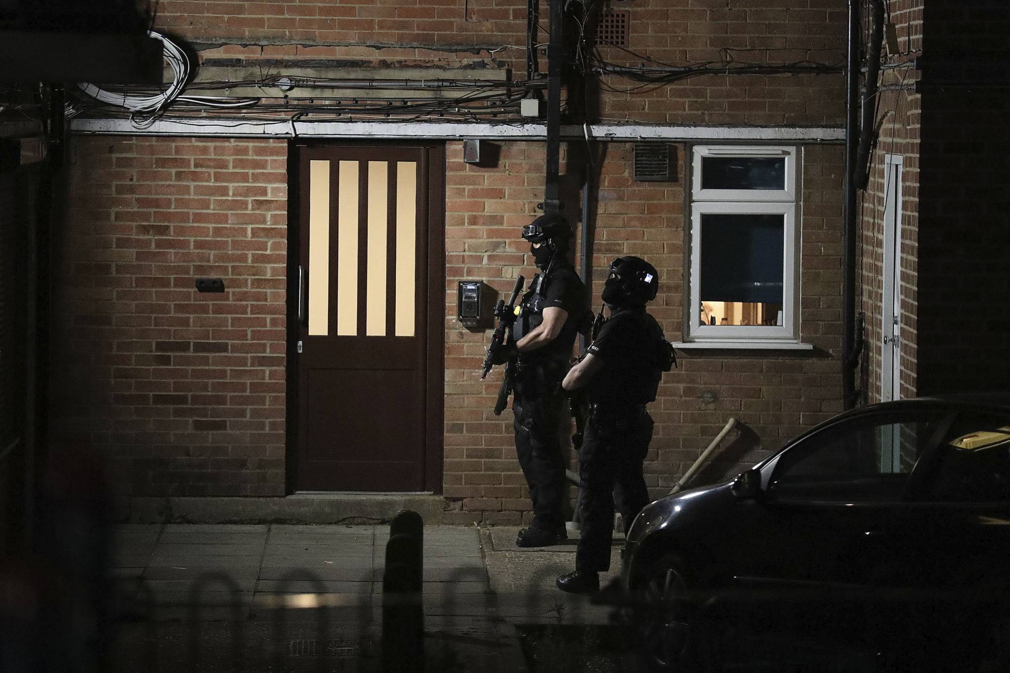 Armed police officers stand near a block of flats in Reading, England, after several people were injured in a stabbing attack at Forbury Gardens park.  | PA / VIA AP