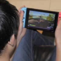 A junior high school student plays a game on a hand-held console at his home in Yokohama last month. | KYODO