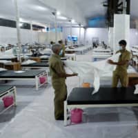 Workers prepare a bed at a recently constructed quarantine facility for COVID-19 patients in Mumbai on Monday.  | REUTERS 