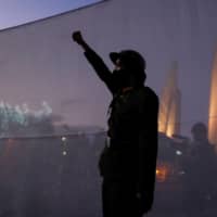 A demonstrator dressed in a vintage uniform raises his fist next to images of the 1932 coup in Thailand, in Bangkok on Wednesday.  | REUTERS
