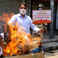 Protesters burn an image of Chinese President Xi Jinping at a demonstration requesting consumers to boycott Chinese goods in New Delhi on Monday. | BLOOMBERG
