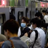 People line up to board trains during the evening rush hour in Tokyo on Wednesday. | AFP-JIJI
