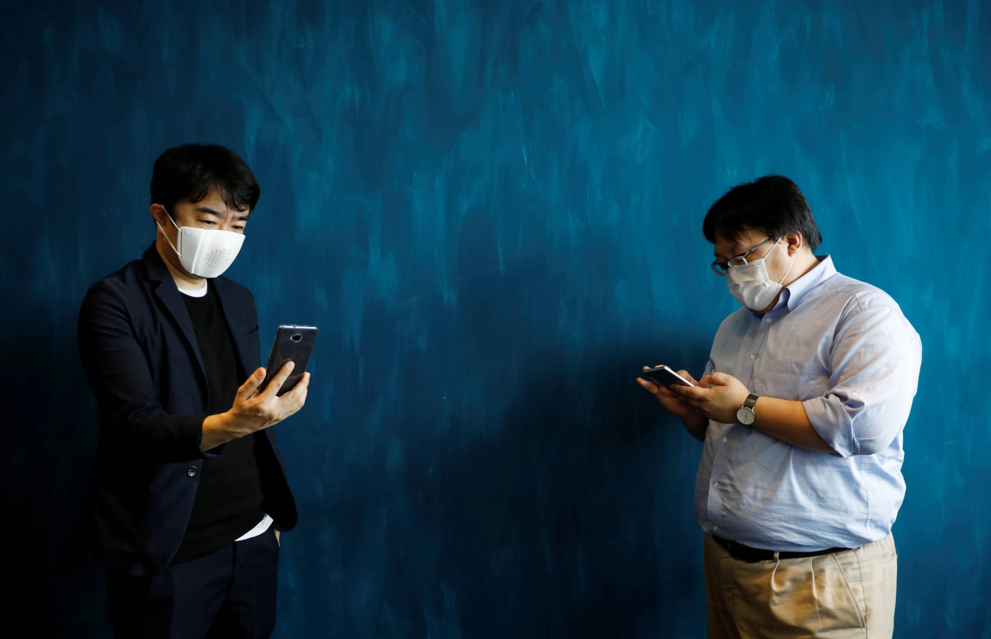 Japanese startup Donut Robotics' CEO Taisuke Ono wears a c-mask as he demonstrates the connected face masks messaging function with his chief engineer, Takafumi Okabe, during a demonstration in Tokyo on Tuesday. | REUTERS