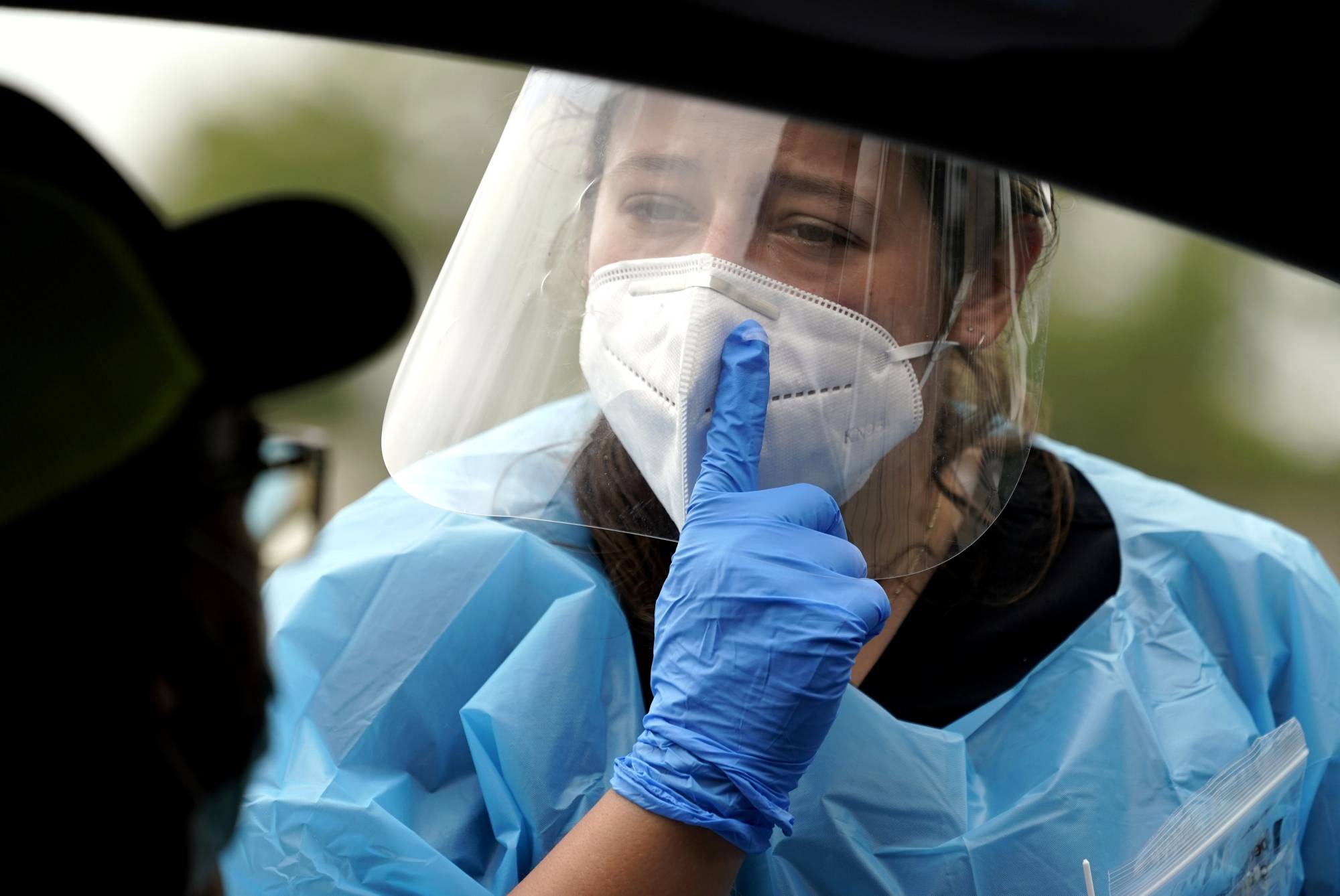 A health care professional Kenzie Anderson explains how she will take a sample to a patient at a testing site Friday in Houston. | AP