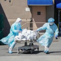 Bodies are moved to a refrigeration truck serving as a temporary morgue in Brooklyn, New York, in April.  | AFP-JIJI