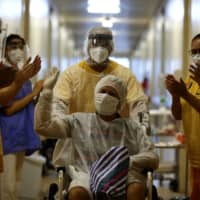 A patient gestures as he leaves the Nossa Senhora da Conceicao Hospital after being treated for COVID-19 in Porto Alegre, Brazil, in April.  | REUTERS 