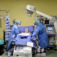 A patient suffering from COVID-19 is treated in an intensive care unit at the San Raffaele hospital in Milan, Italy, in March.  | REUTERS 