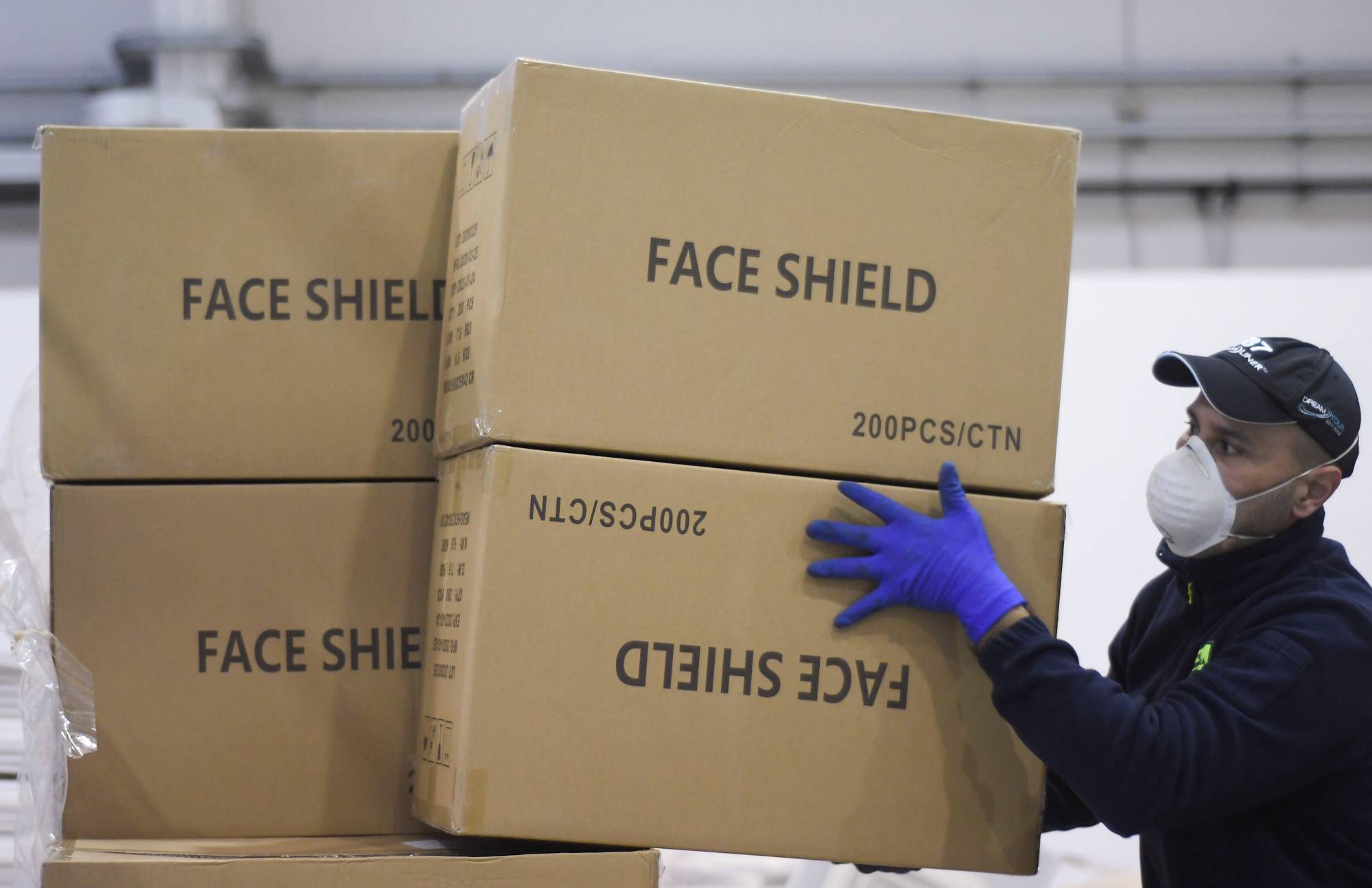 A worker piles up a shipment containing supplies of personal protective equipment to help the southern Italian region of Puglia combat the spread of COVID-19, in Bari, Italy, in April. | Reuters 