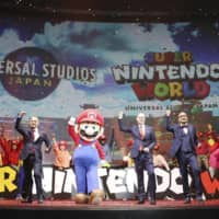 Mario and officials pose for a photo in Osaka in January at a news conference to announce a plan to open the Nintendo-themed area in Universal Studios Japan. | KYODO