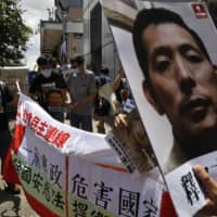 Pro-democracy demonstrators hold up portraits of jailed Chinese civil rights activists, lawyers and legal activists as they march to the Chinese liaison office in Hong Kong on Thursday.  | AP