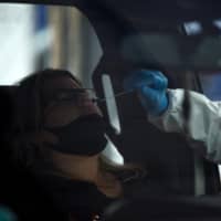 A health care worker administers a COVID-19 test in Houston on Thursday. | AFP-JIJI
