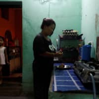 Nepali housewife Shiba Kala Limbu peels potatoes to cook as her five-year-old daughter Masim Limbu enters the room in Kathmandu, Nepal, on Thursday. | REUTERS