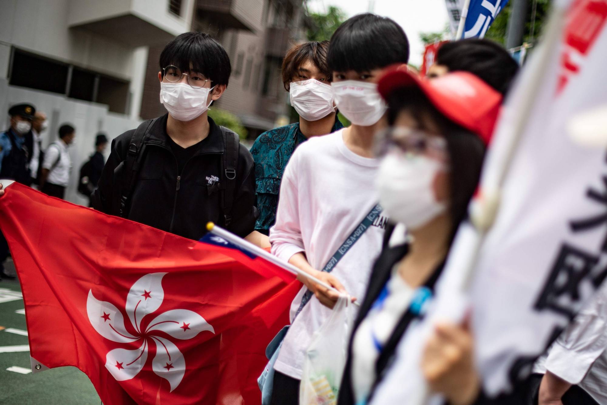 A group of pro-democracy activists hold a Hong Kong flag as they walk to the Chinese Embassy in Tokyo during a protest march on June 4. | AFP-JIJI