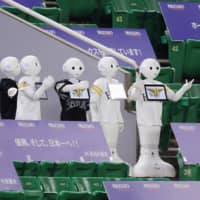 \'Pepper\' robots dance at PayPay Dome in Fukuoka during an NPB opening day game between the Hawks and Marines on June 19. | KYODO