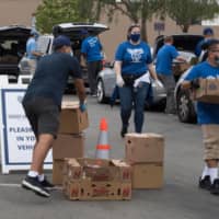 Staff and volunteers with The Los Angeles Dodgers Foundation distribute food and other goods for people facing economic hardship in Huntington Park, California, on June 18. | AFP-JIJI