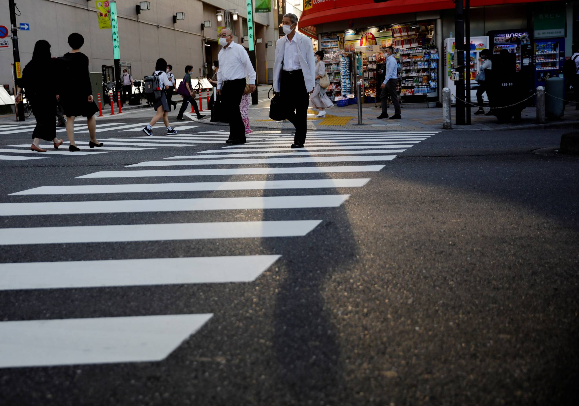 Pedestrians wearing protective masks make their way through downtown Tokyo on Monday. | REUTERS