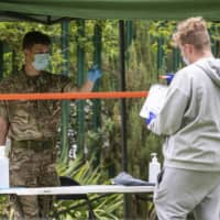 Members of the British military operate a walk-in mobile COVID-19 testing center at Spinney Hill Park in Leicester, England, on Monday. | AP