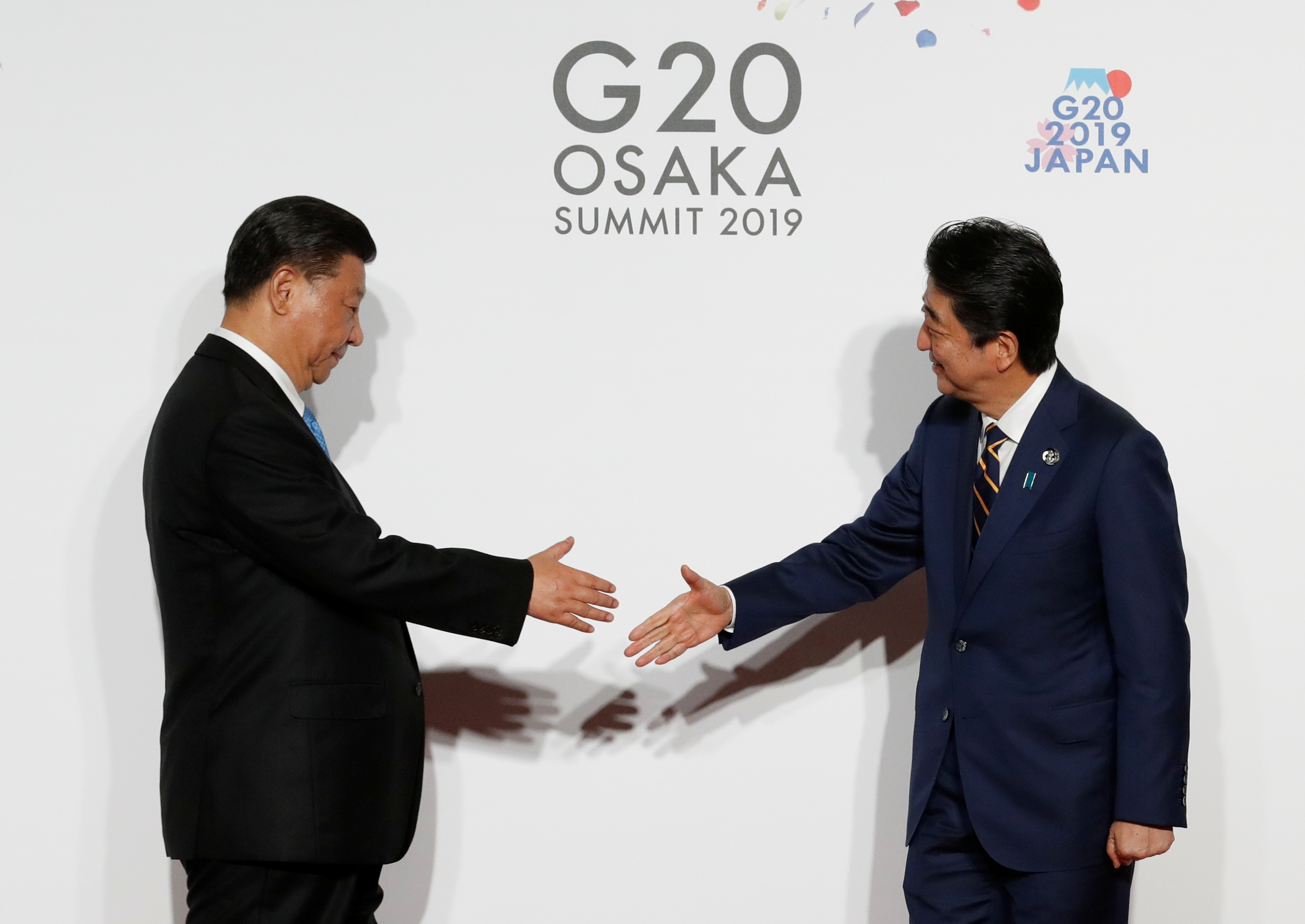 Chinese President Xi Jinping is welcomed by Prime Minister Shinzo Abe upon his arrival for a family photo session at at the Group of 20 summit in Osaka last June. China hawks among Japan's conservatives, long divided on Beijing, have gained ground recently as its diplomatic and military clout grows. | POOL / VIA REUTERS