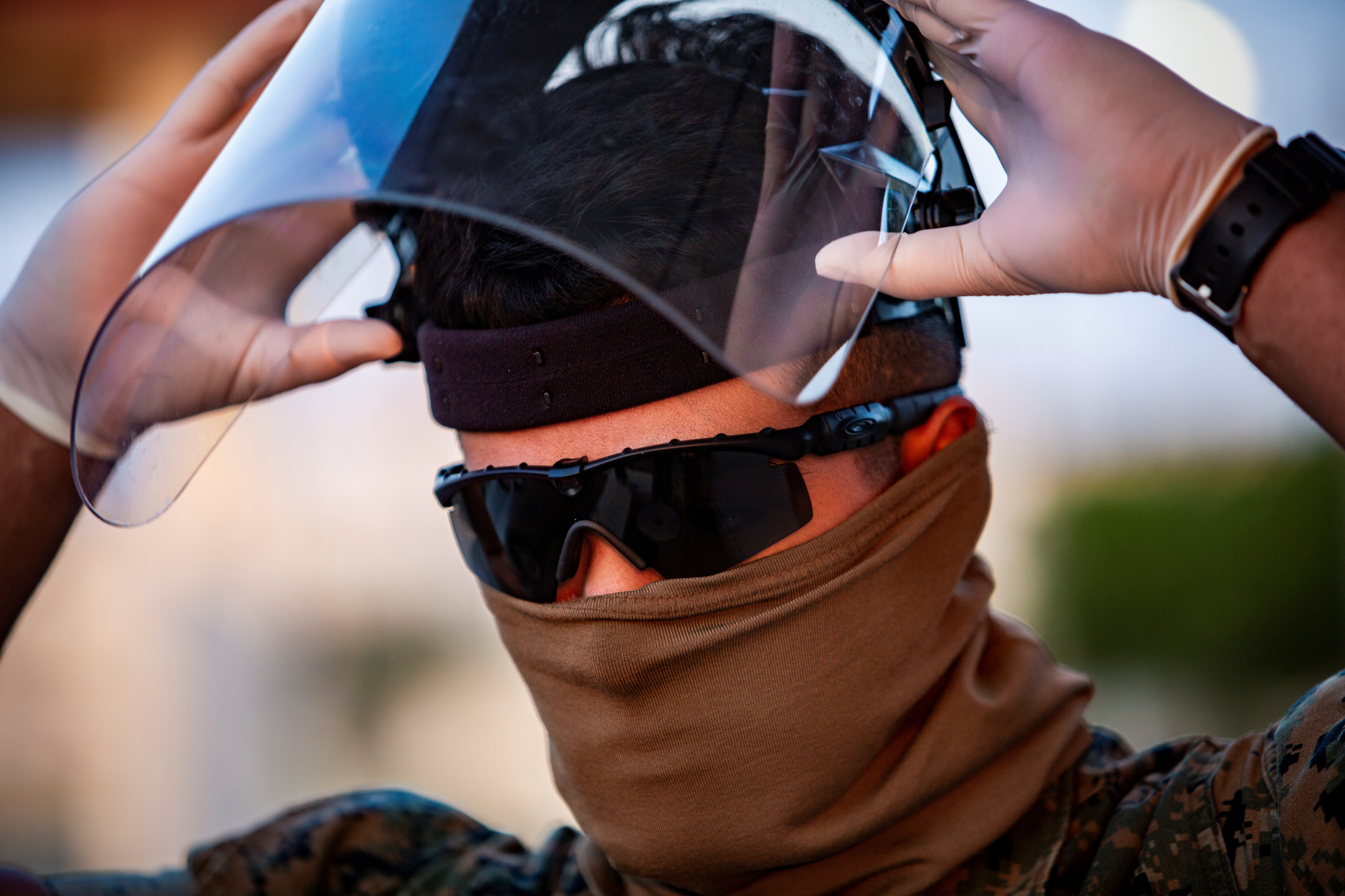 A U.S. Marine dons personal protective equipment (PPE) to begin screening incoming personnel in response to the increased threat of COVID-19 at Camp Foster, in Okinawa Prefecture, in April 10. | U.S. MARINE CORPS / VIA REUTERS