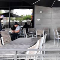 A waiter walks past a few customers dining outdoors at a restaurant in Los Angeles on Monday, a day after the state\'s governor ordered the immediate closure of bars in a number of California counties.  | AFP-JIJI