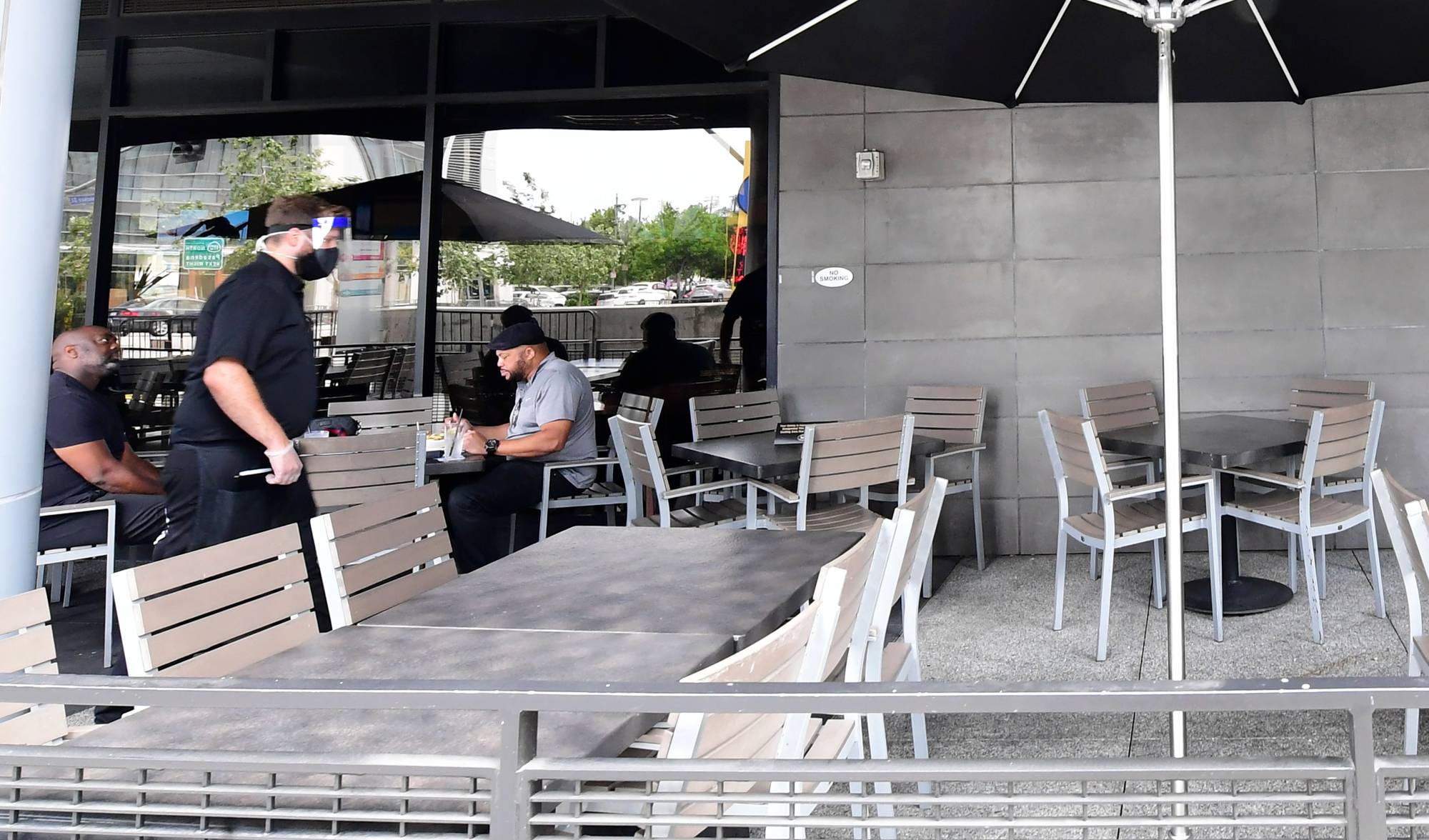 A waiter walks past a few customers dining outdoors at a restaurant in Los Angeles on Monday, a day after the state's governor ordered the immediate closure of bars in a number of California counties.  | AFP-JIJI