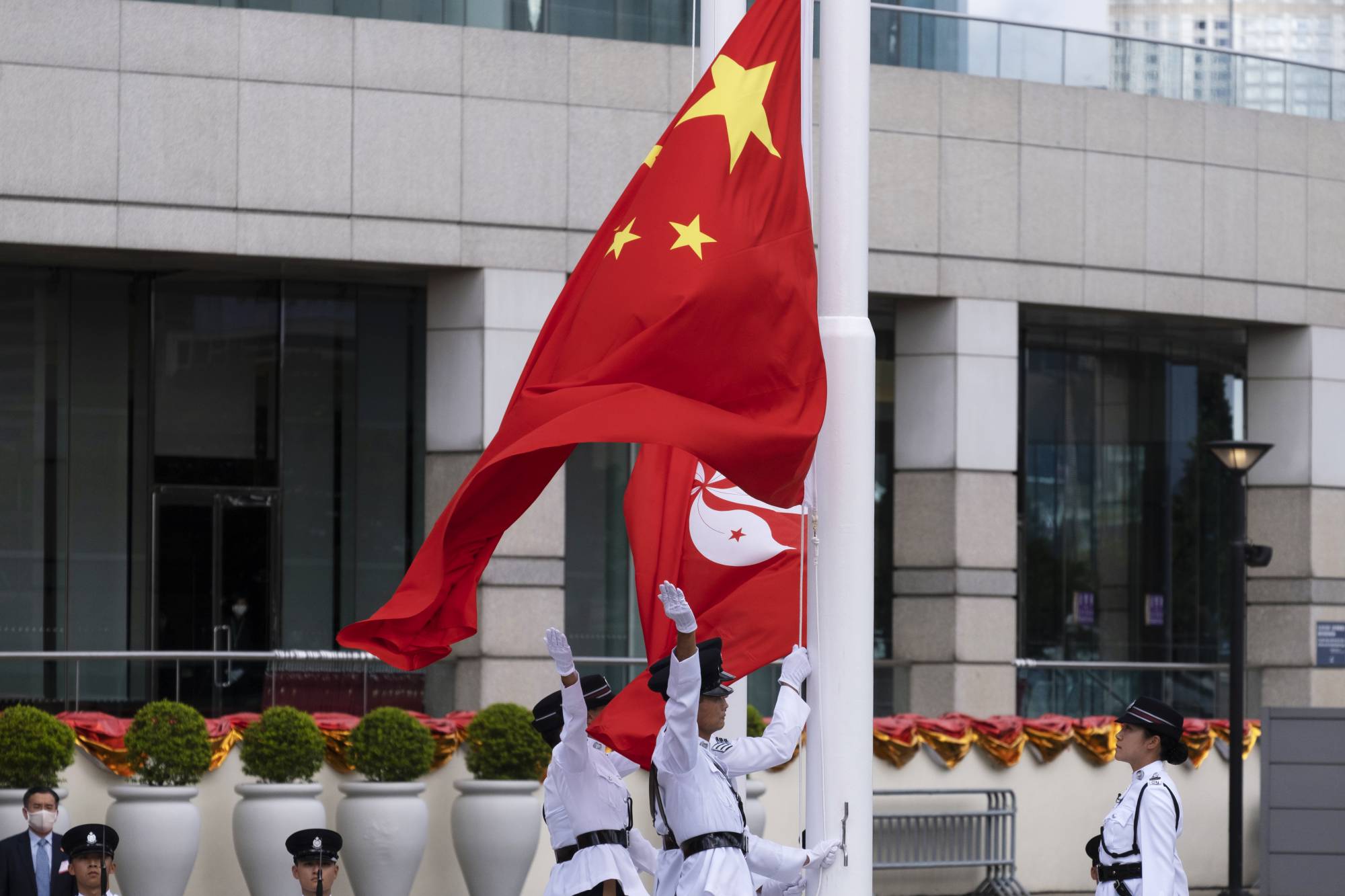 The flags of China and Hong Kong are raised during a ceremony to mark the 23rd anniversary of Hong Kong's return to Chinese rule on Wednesday in the financial hub. | BLOOMBERG