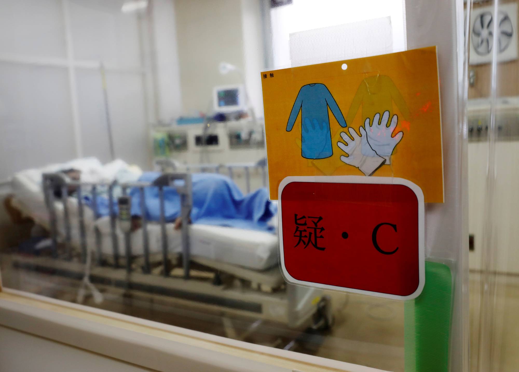 A patient rests in an intensive care unit at Seibu Hospital that is marked with a sign indicating he is suspected of having COVID-19, in Yokohama on June 18. | REUTERS