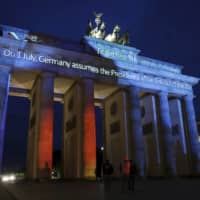 The Brandenburg Gate is illuminated on Monday to mark Germany\'s July 1 assumption of the EU Council presidency. The European Union\'s largest economy is taking the chair of the 27-nation bloc amid massive challenges and huge expectations as the continent grapples with the fallout from the coronavirus pandemic. | AP