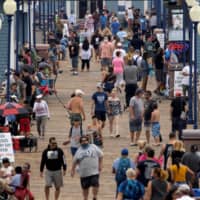 Few masks are seen on a crowded beach pier in Oceanside, California, on June 22. | REUTERS