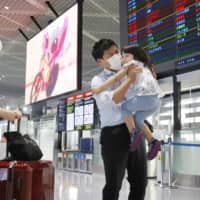 A businessman traveling to Vietnam on a chartered flight says goodbye to his family at Narita Airport on June 25. Japan could soon begin talks with Taiwan and Brunei on easing a travel ban induced by the coronavirus. | KYODO