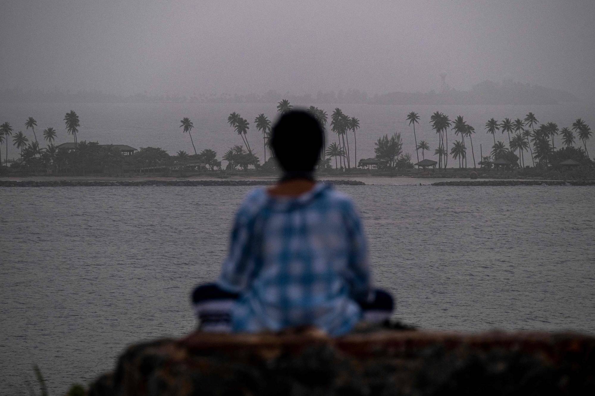 A woman meditates as a vast cloud of Sahara dust blankets the city of San Juan, Puerto Rico, last month.  | AFP-JIJI