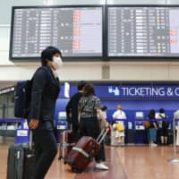 Airline passengers check in at Tokyo International Airport on Saturday. | KYODO