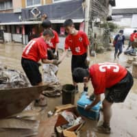 Boys from a local junior soccer team help clean up after mudslides hit Hitoyoshi, Kumamoto Prefecture, on Sunday. | KYODO