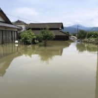 A provided photo shows houses in Asagiri, Kumamoto Prefecture, inundated with water following torrential rains on Saturday. | KYODO