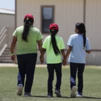 Immigrants seeking asylum leave a cafeteria at the ICE South Texas Family Residential Center in Dilley, Texas. The isolation of at least three families at the site has raised new fears of the coronavirus spreading through a facility that has long been accused of providing substandard medical care.  | AP