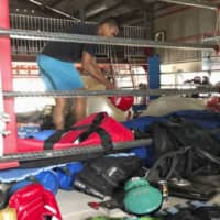 Boxer Sewon Okazawa removes damaged equipment from the ring on Tuesday at his gym in Kanoya, Kagoshima Prefecture, after it was hit by flooding. | KYODO