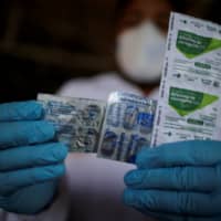 A health care worker holds a packet of hydroxychloroquine sulfate, azitrophar and chloroquine diphosphate at the riverside community of Santo Ezequiel Moreno in Brazil. | REUTERS 
