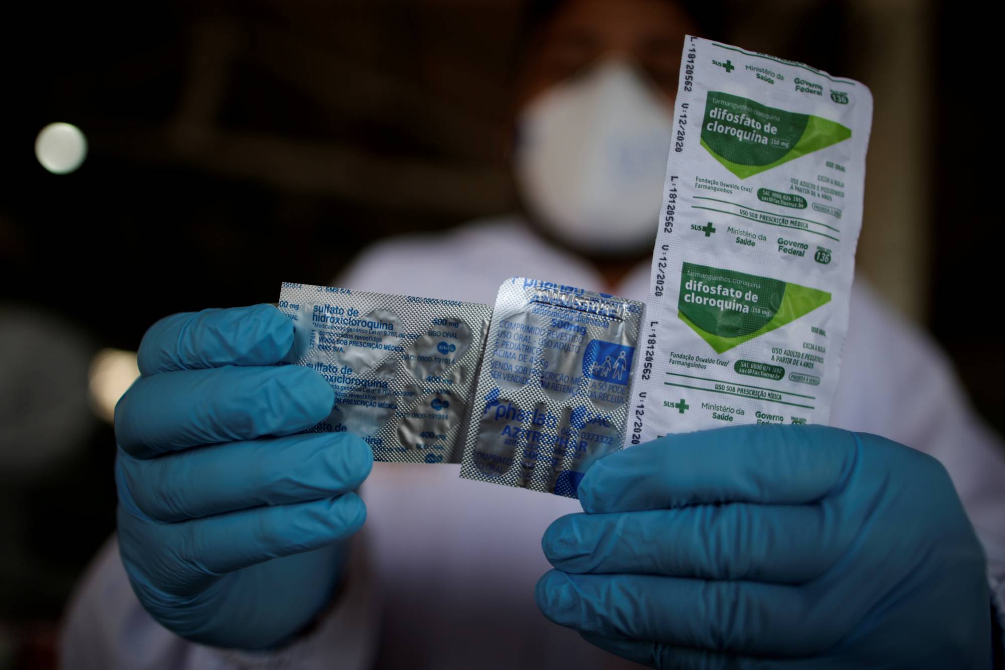 A health care worker holds a packet of hydroxychloroquine sulfate, azitrophar and chloroquine diphosphate at the riverside community of Santo Ezequiel Moreno in Brazil. | Reuters 