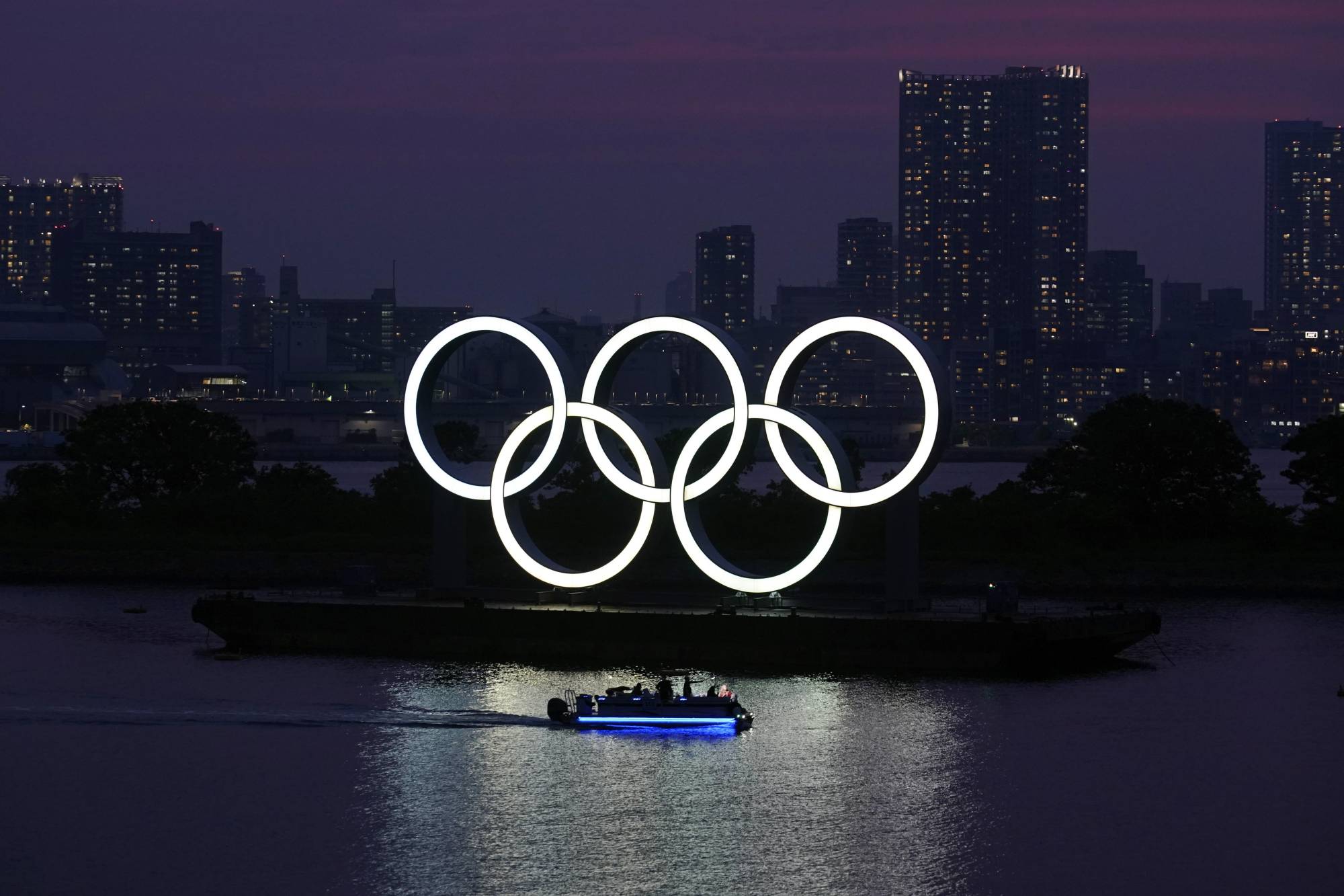 The Olympic rings float in the water at sunset in Tokyo's Odaiba waterfront district. | AP 