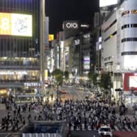 Pedestrians cross an intersection at night in the Tokyo\'s Shibuya Ward on Friday. | BLOOMBERG