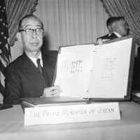 Prime Minister Nobusuke Kishi displays the United States-Japan security treaty after the signing ceremony at the White House on Jan. 9, 1960. The man who stabbed him on July 14 that year said he was unhappy with Kishi’s handling of the ratification process and wanted to punish him. | AP