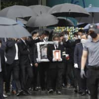 A man holds a portrait of late Seoul Mayor Park Won-soon as mourners leave Seoul City Hall after his official funeral on Monday.  | AP