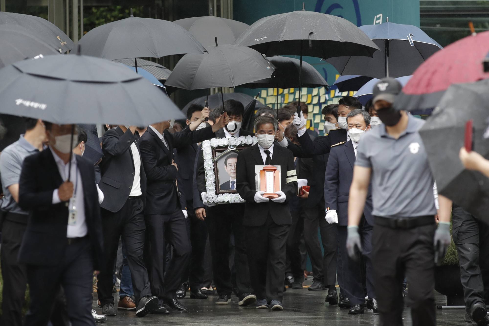 A man holds a portrait of late Seoul Mayor Park Won-soon as mourners leave Seoul City Hall after his official funeral on Monday. | AP