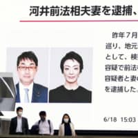 A screen in Tokyo\'s Akihabara district shows a news report that Katsuyuki Kawai and his wife, Anri, were arrested on June 18 on suspicion of vote-buying. | KYODO
